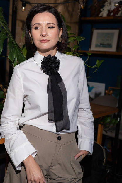Model în cămașă albă și pantaloni bej purtând setul Kallysta negru: broșă din piele naturală și eșarfă din mătase